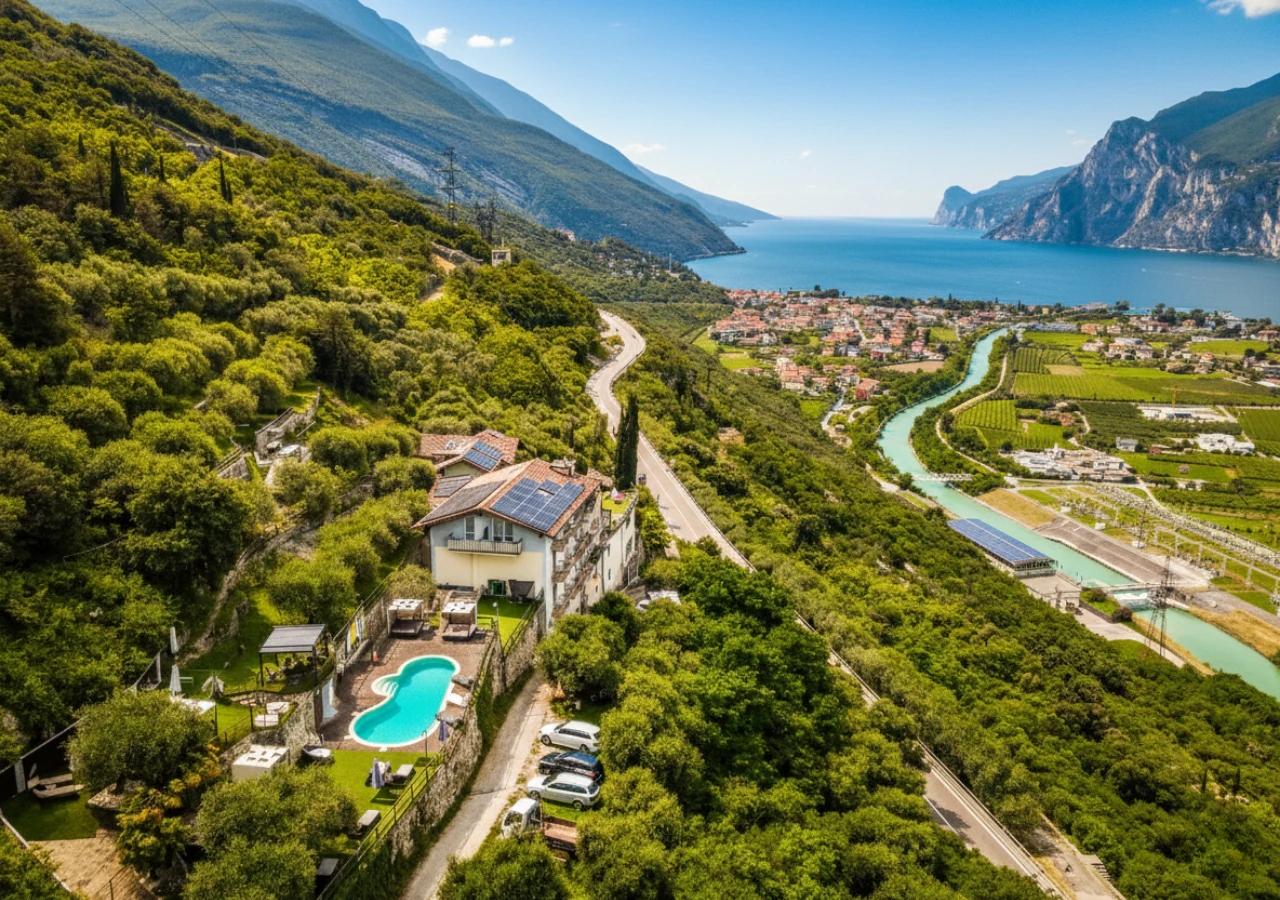 L'hotel con il tetto fotovoltaico e la piscina dall'alto, sotto il lago con Riva e il monte Brione