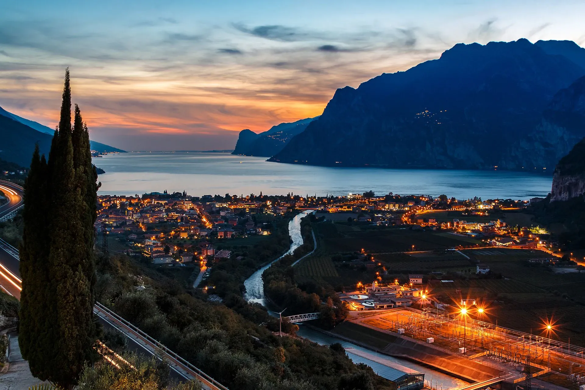 Torbole e il lago al tramonto con le prime luci accese, dalla collina dell'hotel